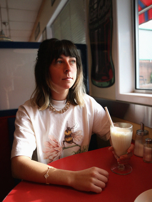 a white cotton t shirt with a high qulaity print of a honey bee doing yoga on a flower